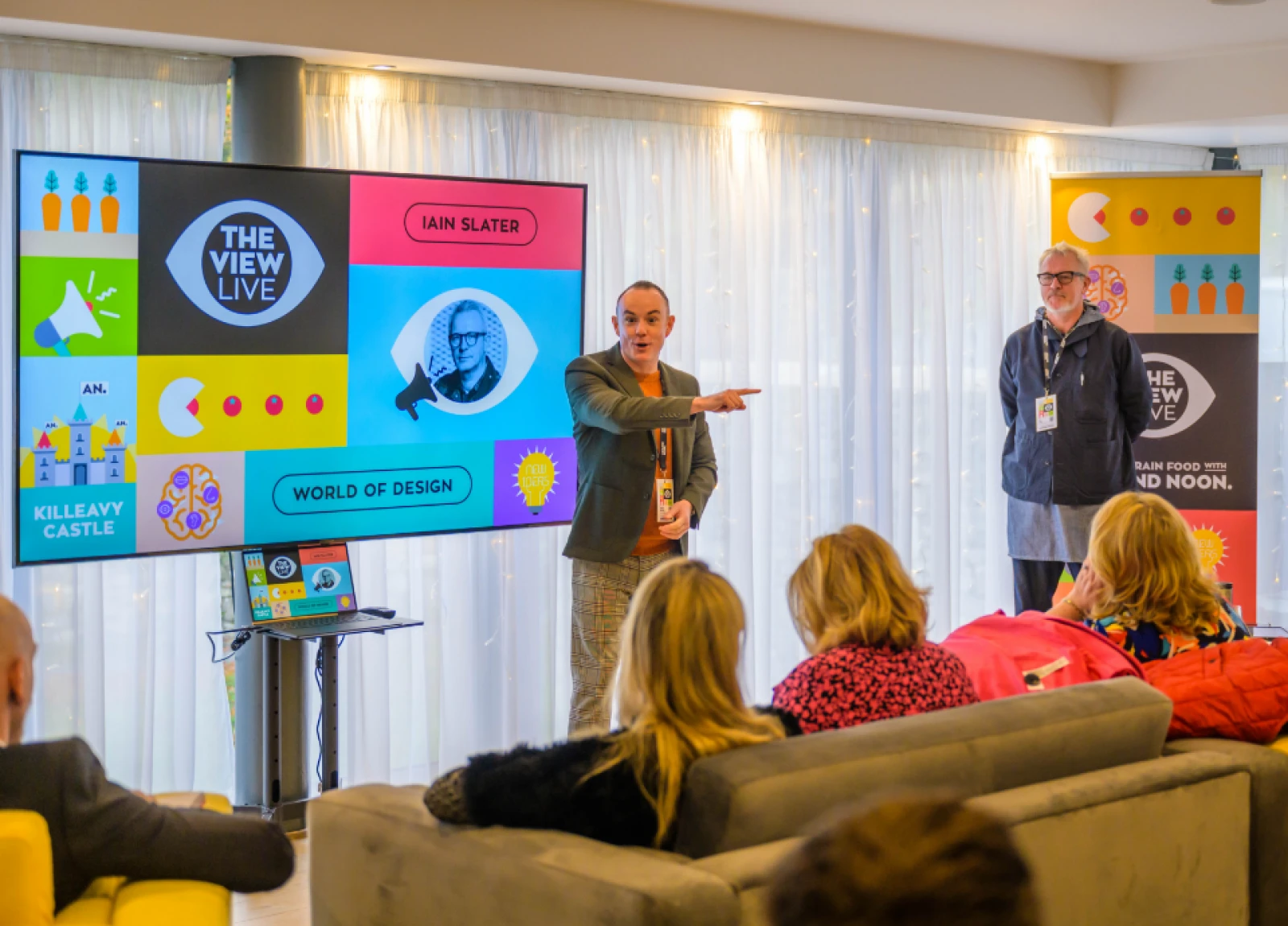 man pointing infront of a group of people while giving a talk